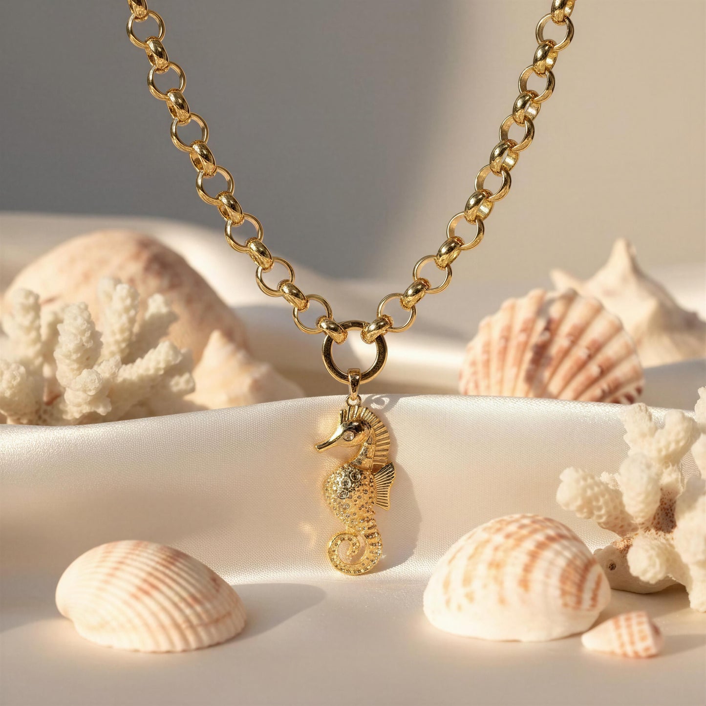 The Chica Chica Jewelry Seahorse Statement Necklace on a sandy background with shells and coral.
