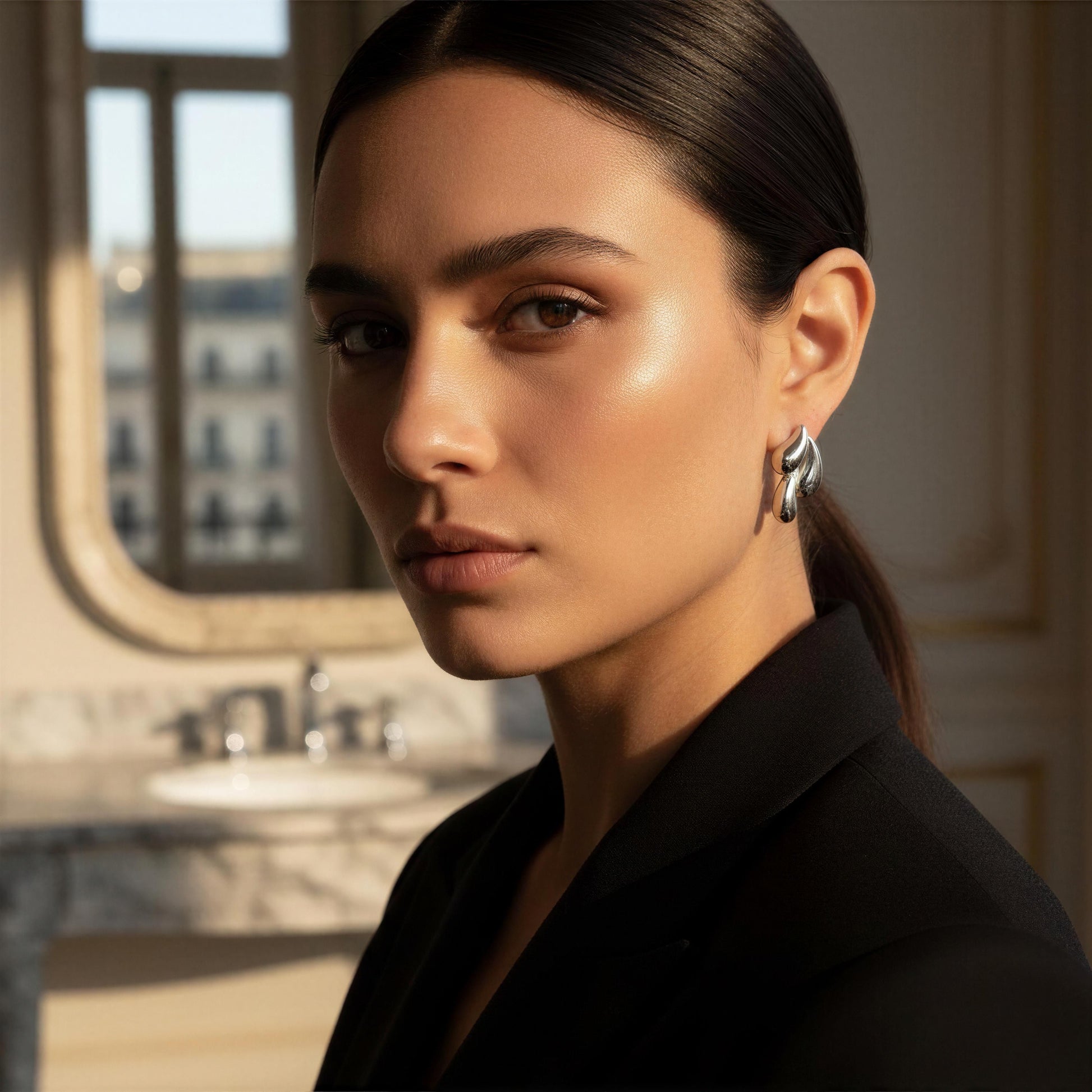 Woman wearing the Silver Molten Wave Drop Earrings in a bathroom setting