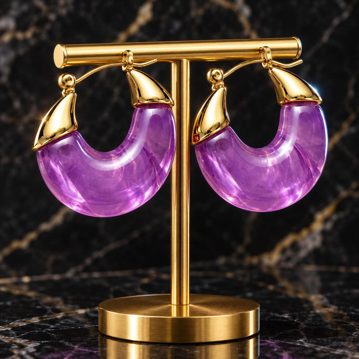 The Soraya Hoops – Violet- Chica Chica Jewelry on marble black table displayed on a gold jewelry stand. 