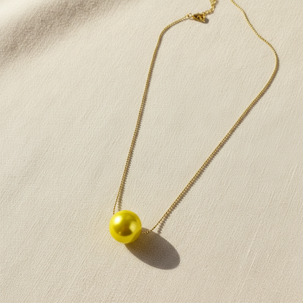 Necklace with a yellow pearl pendant on a beige fabric background