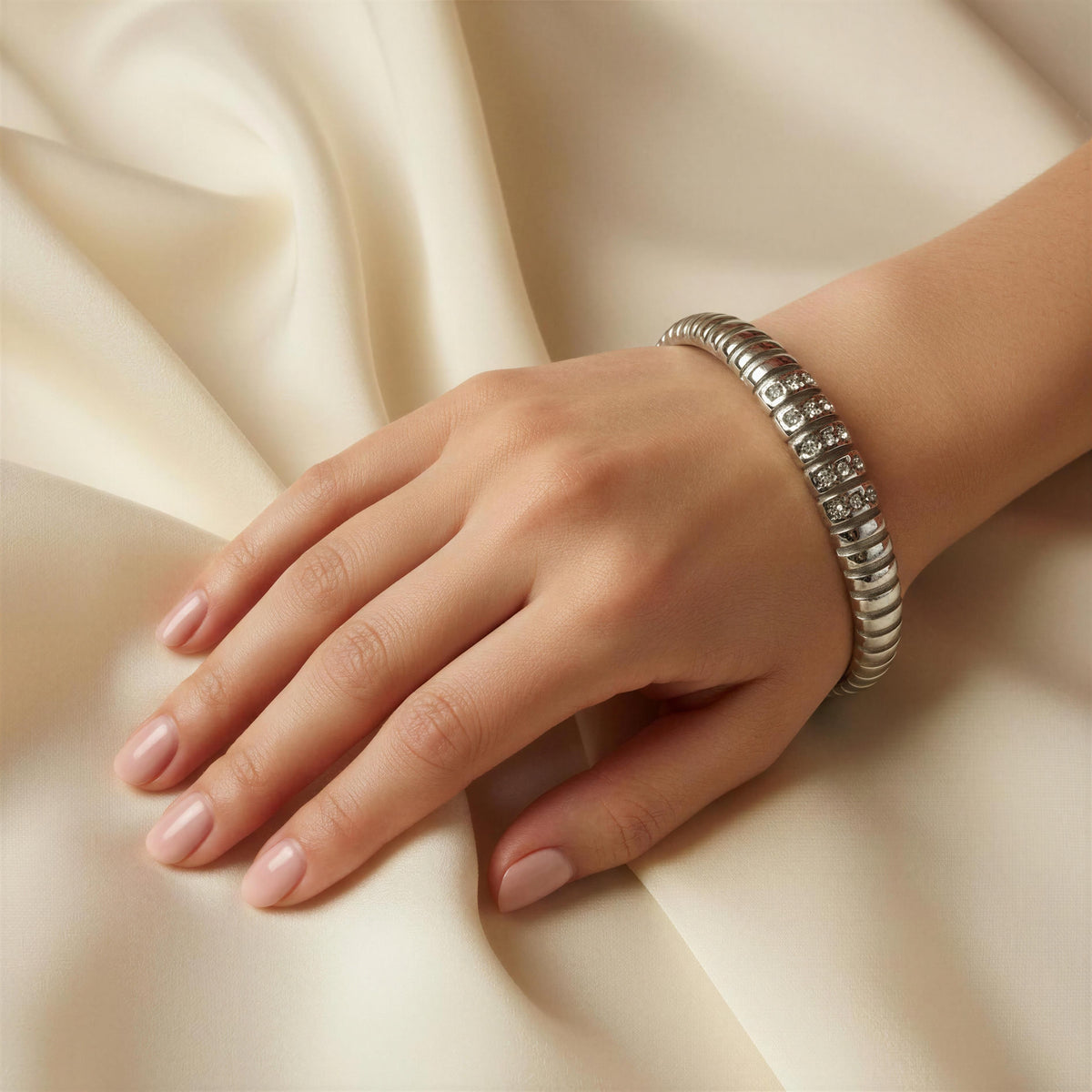 Model hand wearing the Alessia Bangle from Chica Chica Jewelry  against silk crème color fabric 