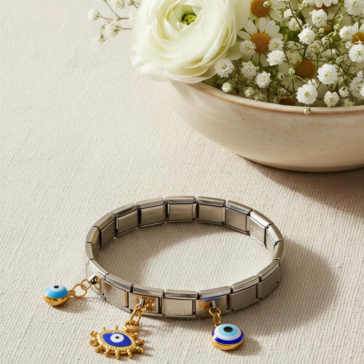 The steel vision bracelet from Chica Chica Jewelry on a light surface with flowers in the background