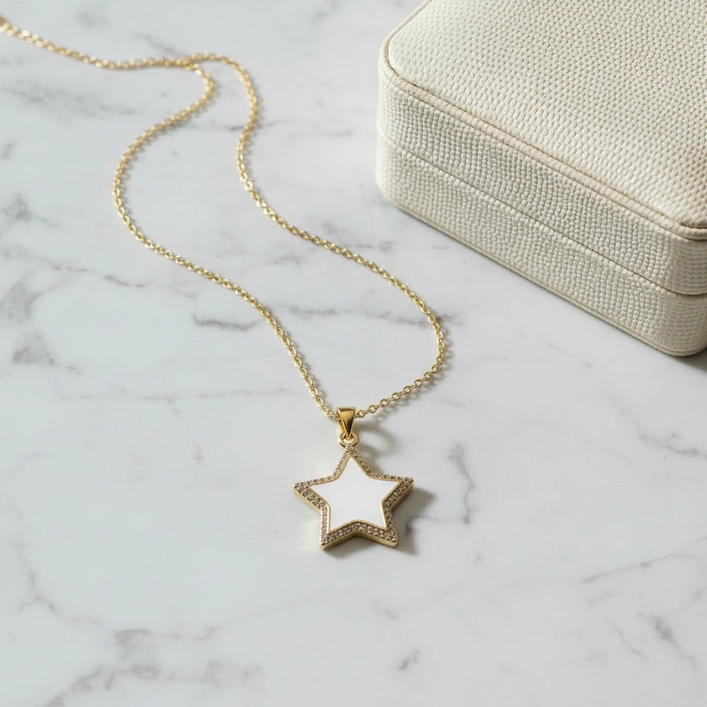 Gold necklace with a star pendant on a marble surface