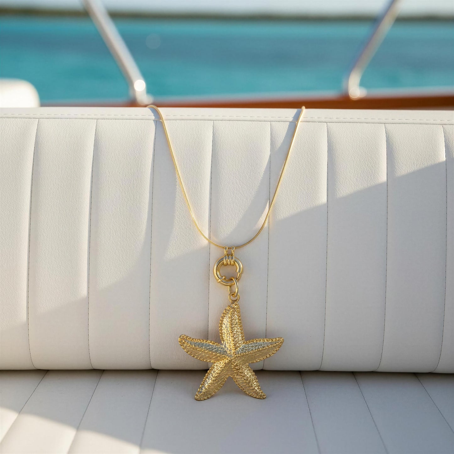 Gold starfish pendant necklace on a white cushion with a blurred outdoor background