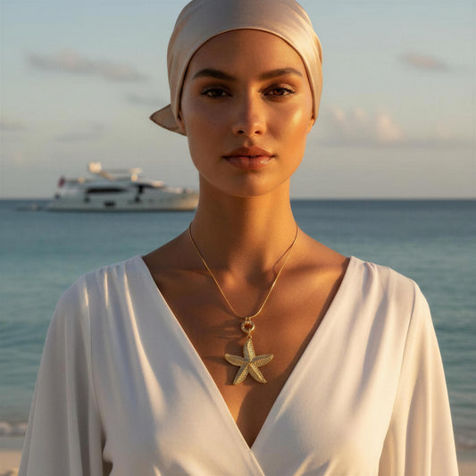 Woman wearing a white dress and the Stella Marina Necklace with a boat and ocean in the background
