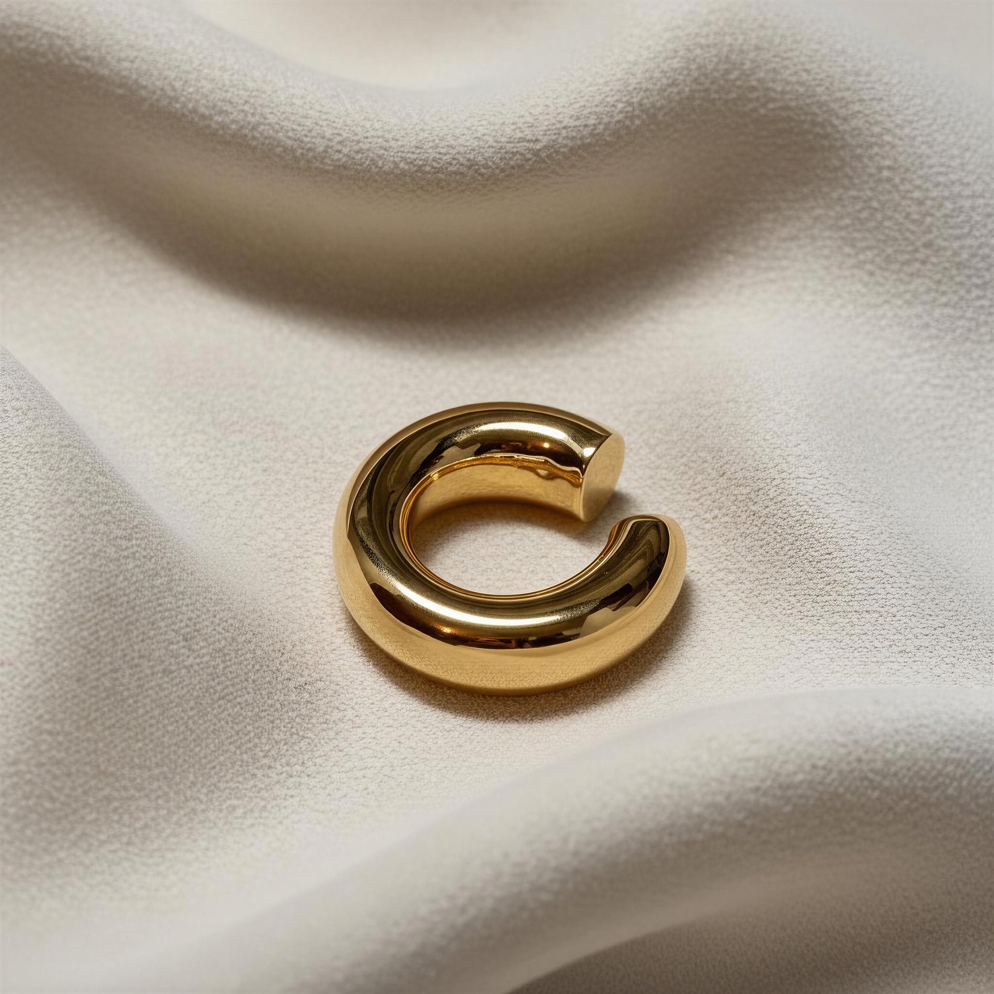 The Stellar Arc Ear Cuff on a soft beige fabric background