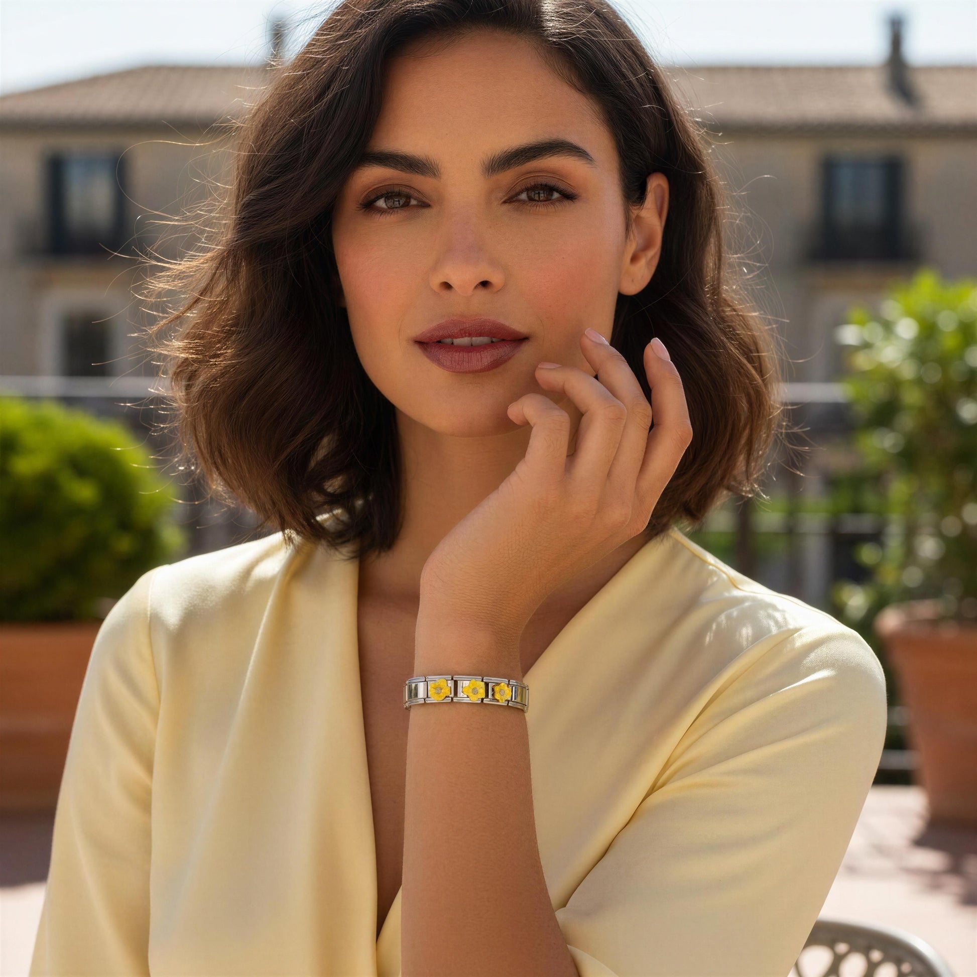Woman in a yellow top with a bracelet, outdoors with plants and building in the background wearing the Sunlit Blossom Bracelet