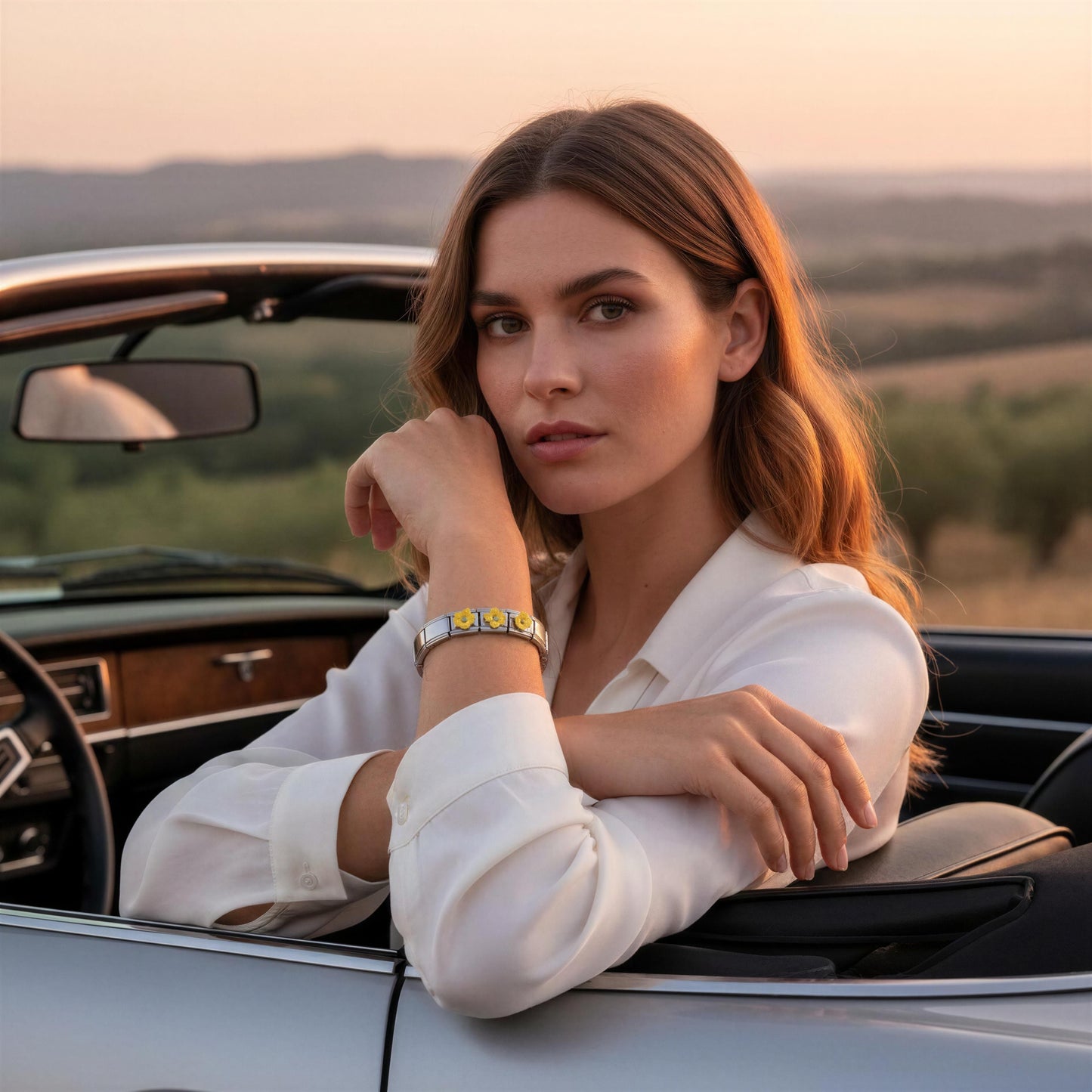 Woman sitting in a convertible car with a scenic background wearing the Sunlit Blossom Bracelet