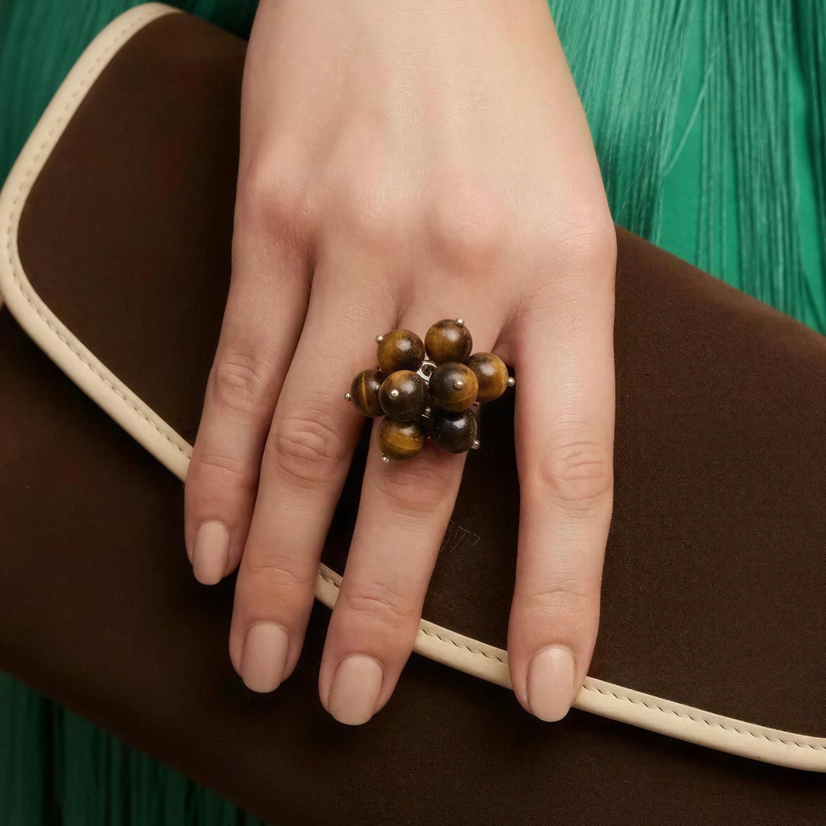 Model wearing the Talia Ring from Chica Chica Jewelry and holding a chocolate and crème color clutch. 