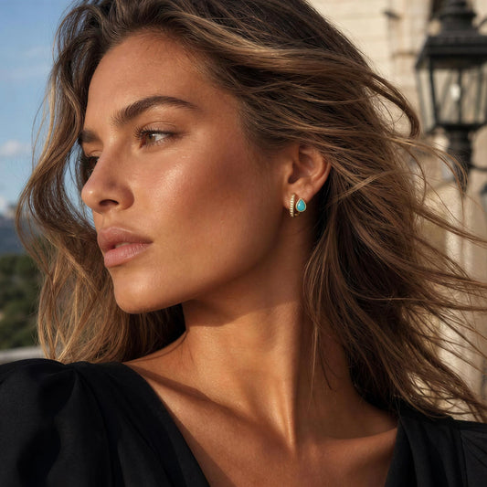 Model wearing a black dress and the Taormina Huggie Earrings  from Chica Chics Jewelry in Turquoise color. 