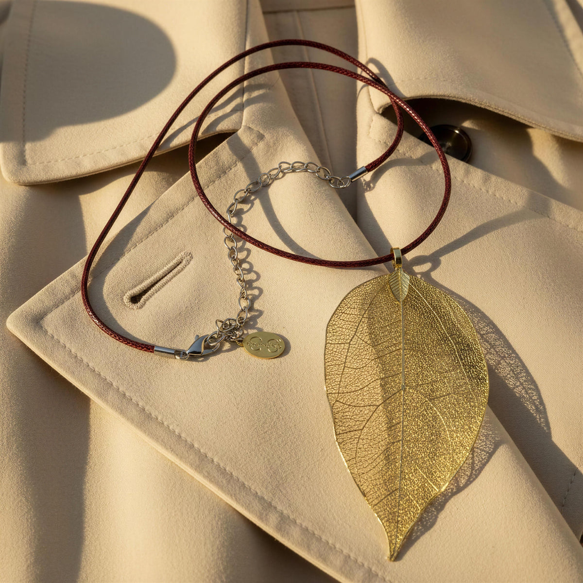 The Aurelia Necklace from Chica Chica Jewelry against a vanilla color trench coat. 
