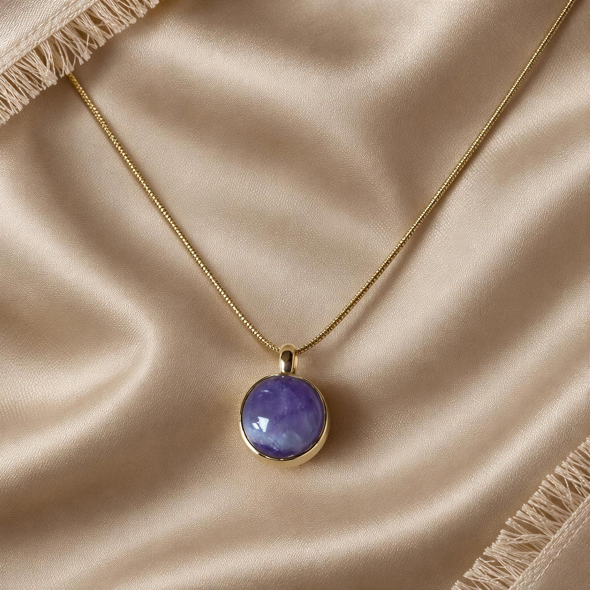 The Lavanda Necklace from Chica Chica Jewelry against a soft vainilla color fabric with fringes.