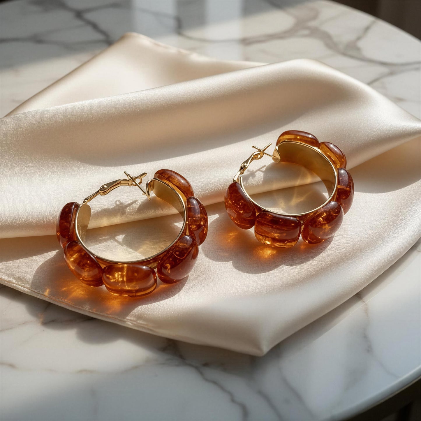Terra Loops Earrings with amber-colored beads on a marble surface