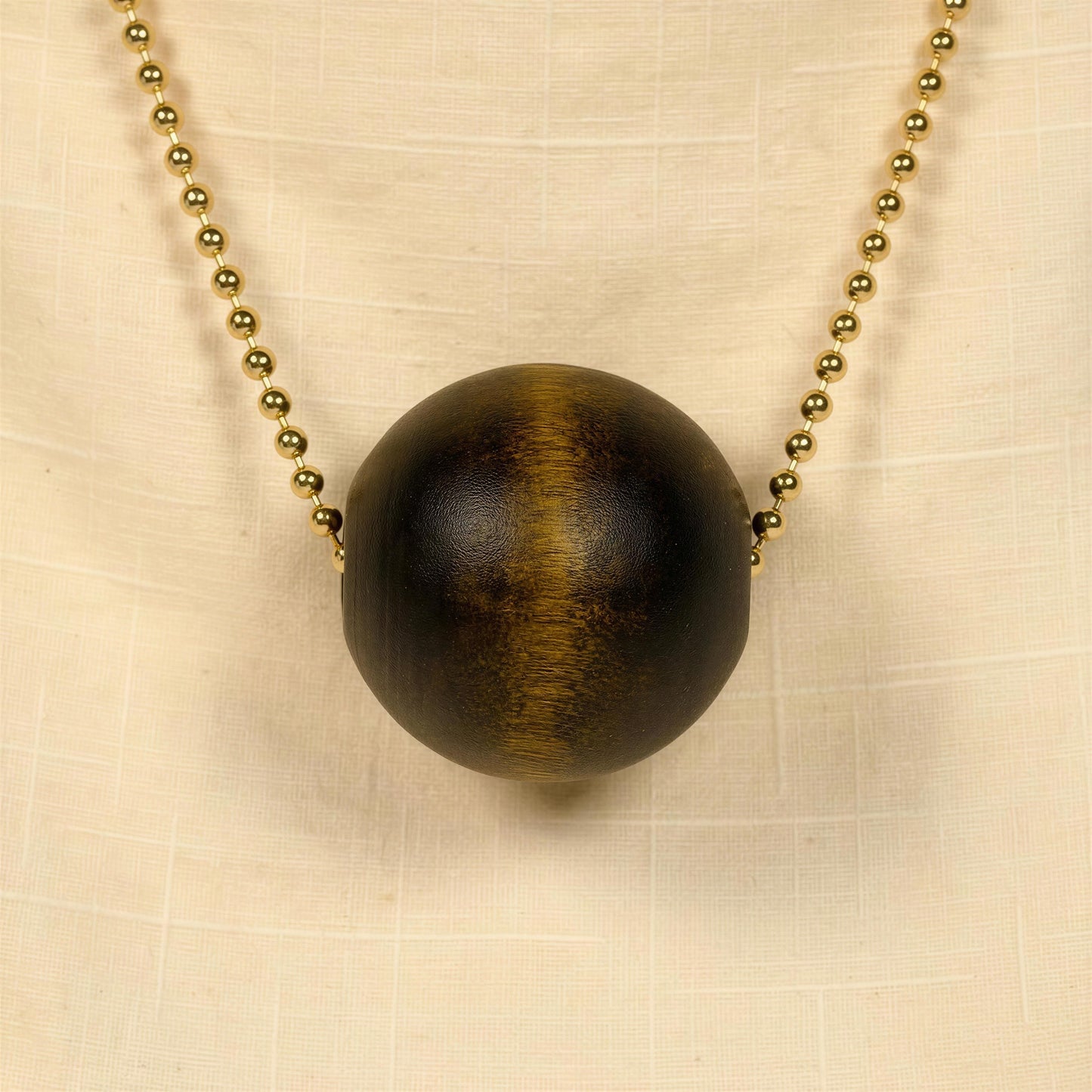Necklace with a large brown wooden bead on a beige fabric background