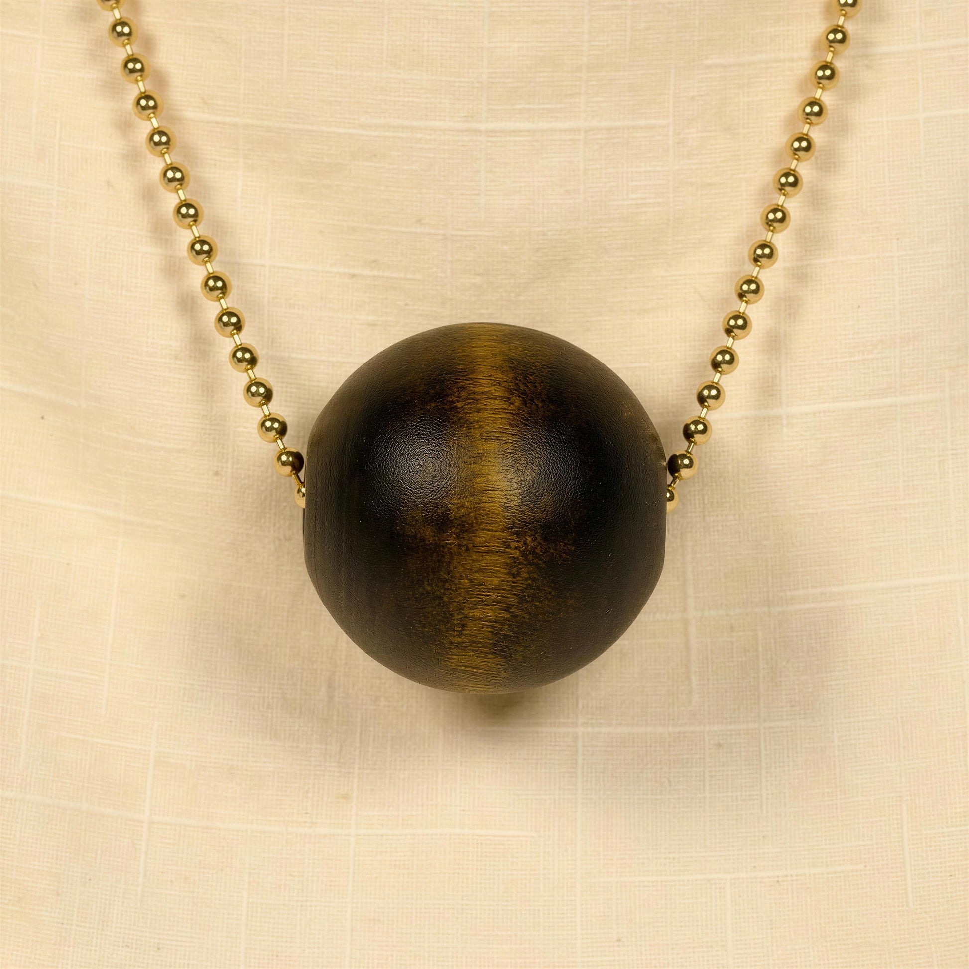 Necklace with a large brown wooden bead on a beige fabric background