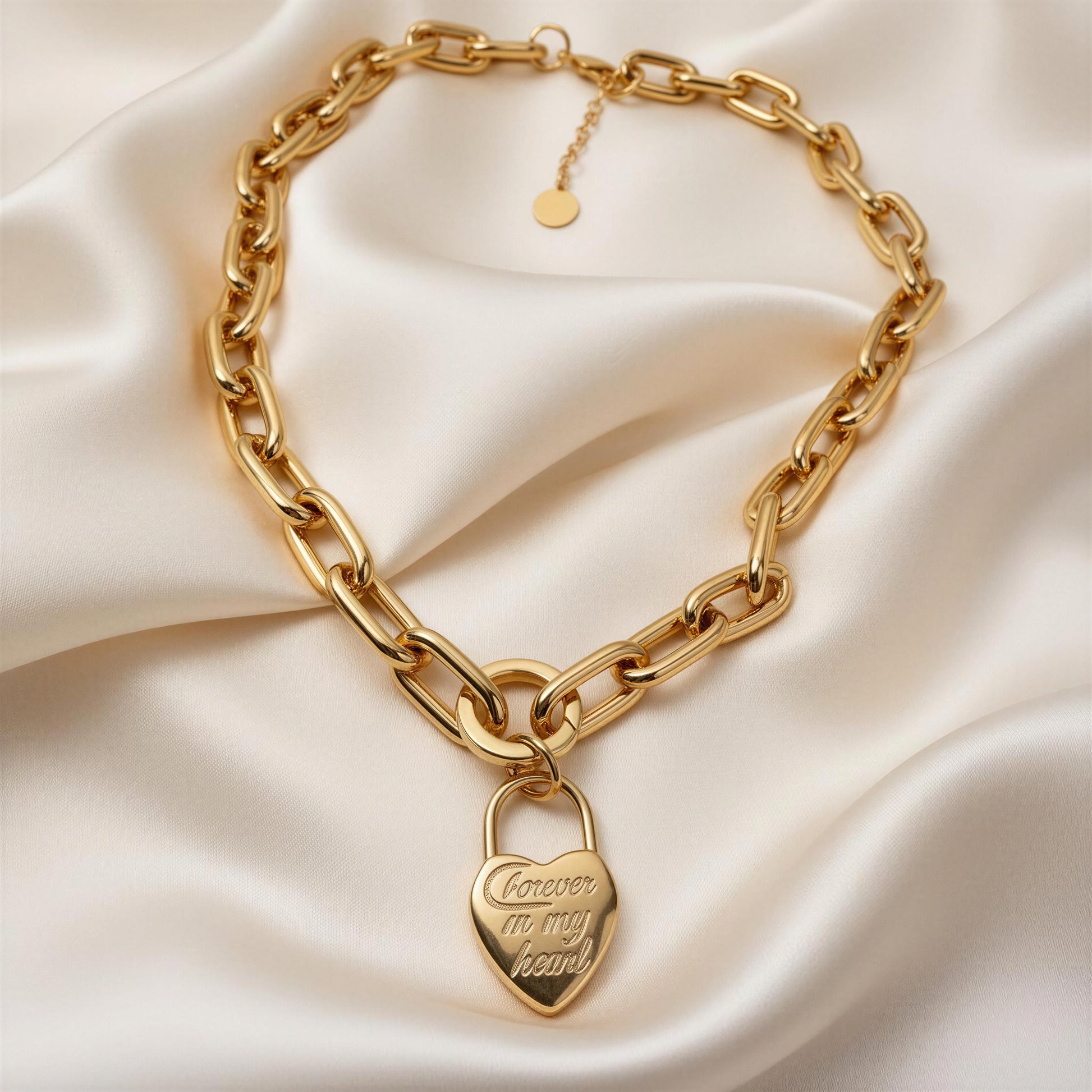 Gold chain necklace with a heart-shaped lock pendant on a beige fabric background