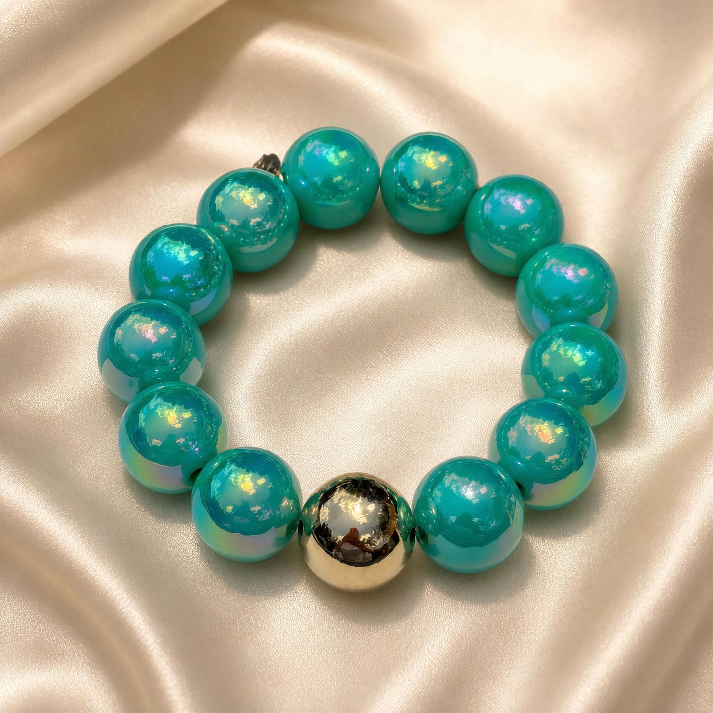 Turquoise beaded bracelet with a gold accent on a satin surface