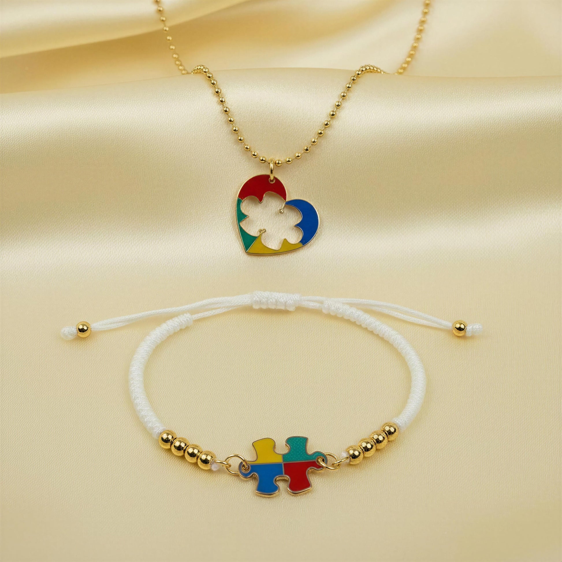 Necklace and bracelet set with colorful heart and puzzle piece designs on a beige fabric background
