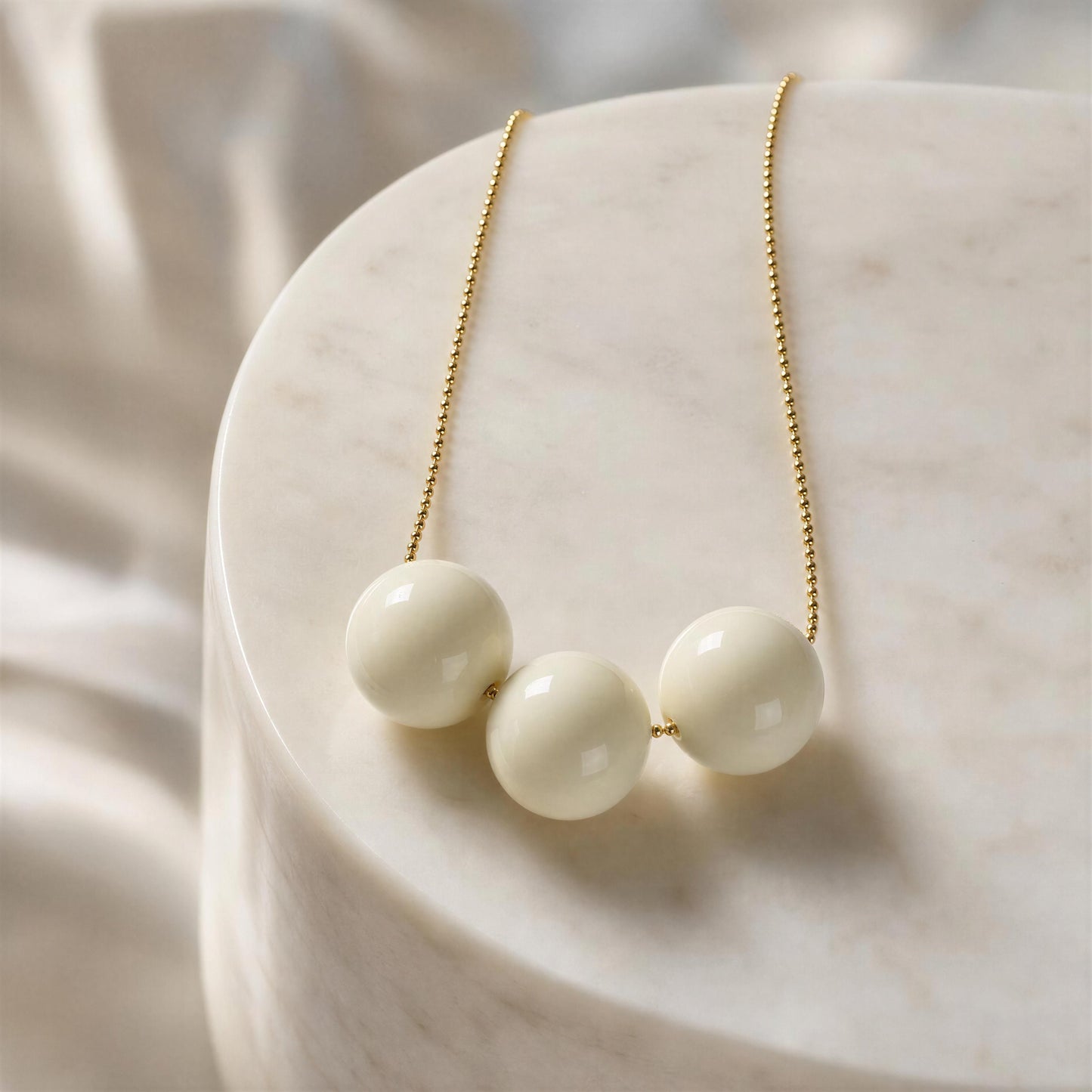 The Calla Necklace with gold chain on a marble surface