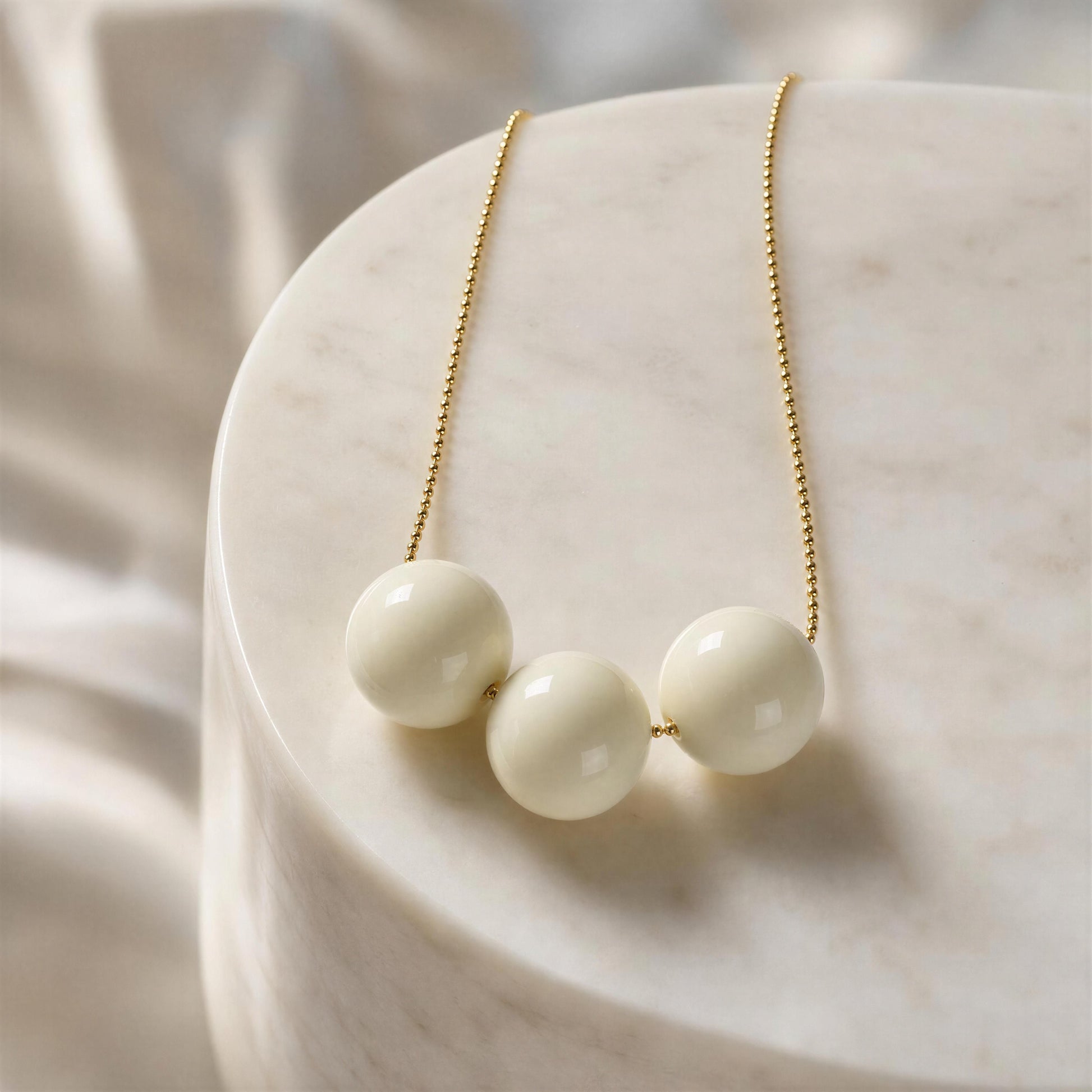 The Calla Necklace with gold chain on a marble surface