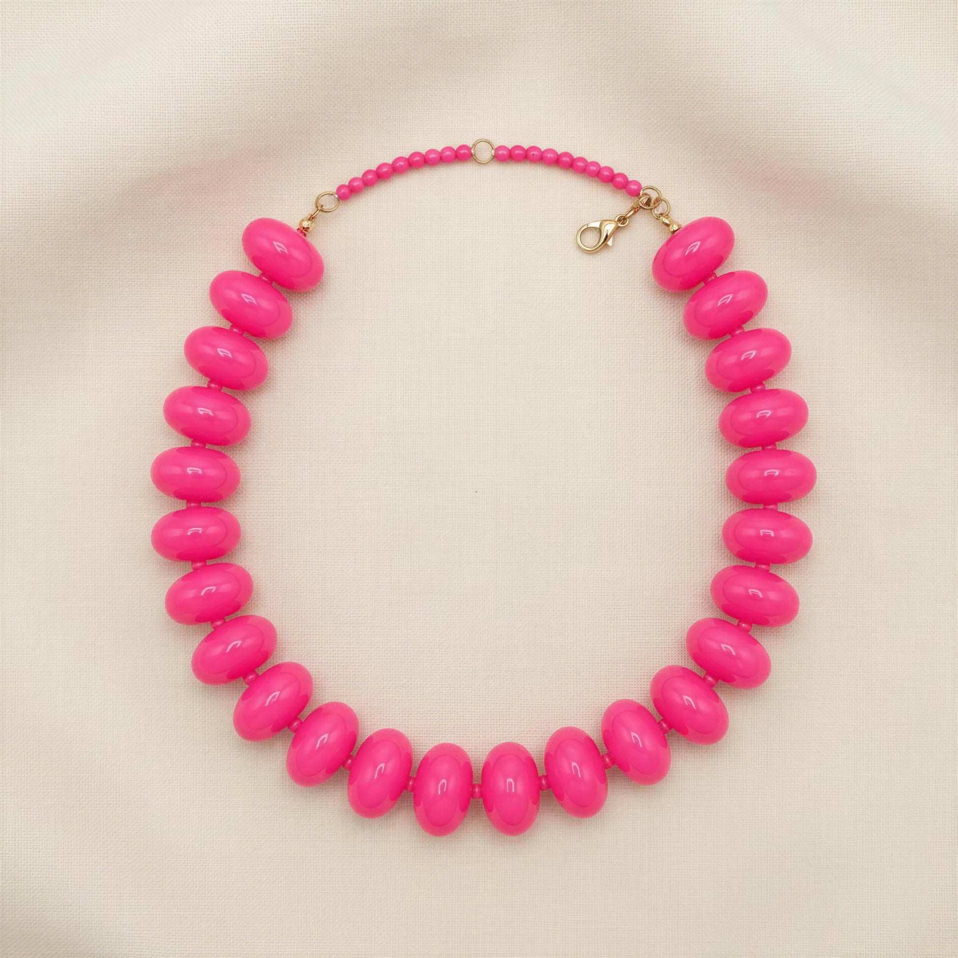 Necklace with bright pink beads on a beige background