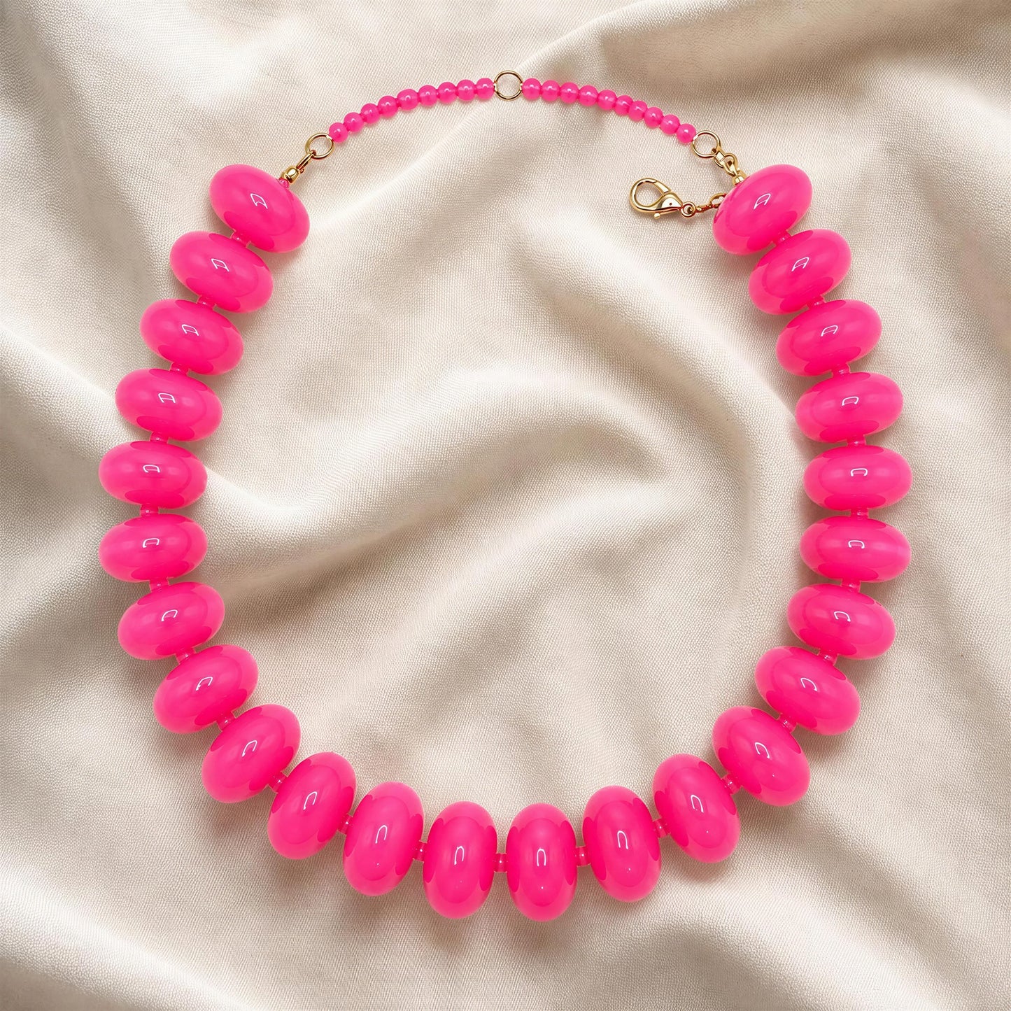The Capri Fuchsia Statement Choker on a beige fabric background