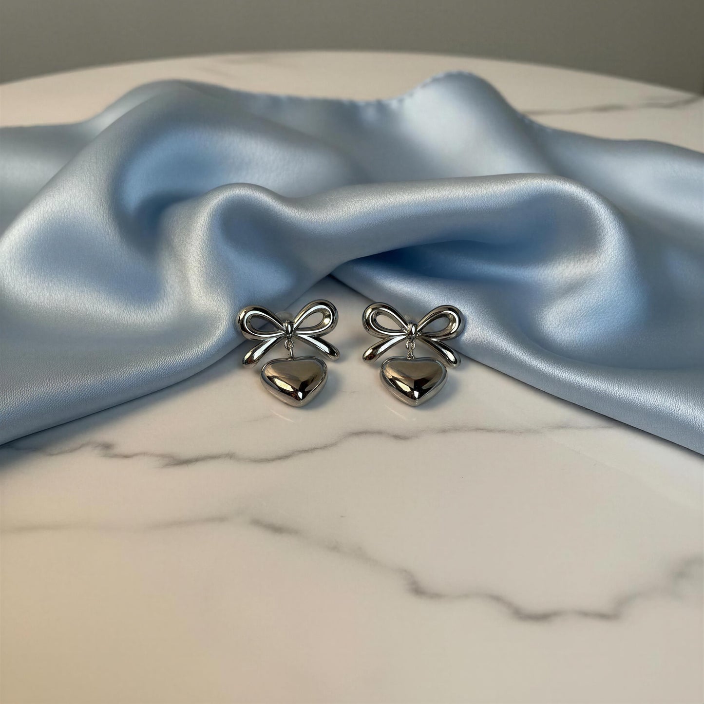 Cupid's Knot Earrings - Silver on marble table with light blue silk scarf 