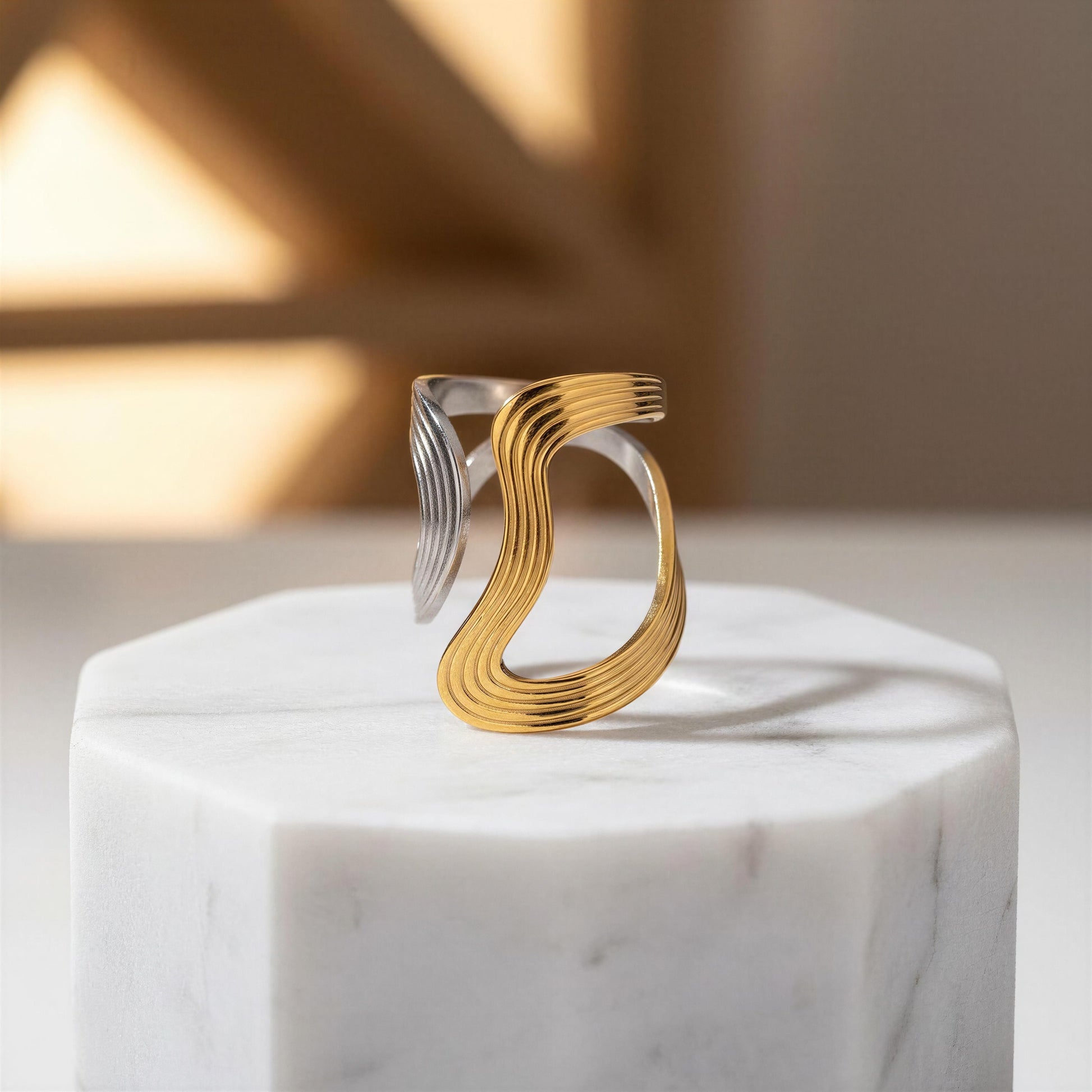 Gold and silver ring on a marble pedestal with a soft background