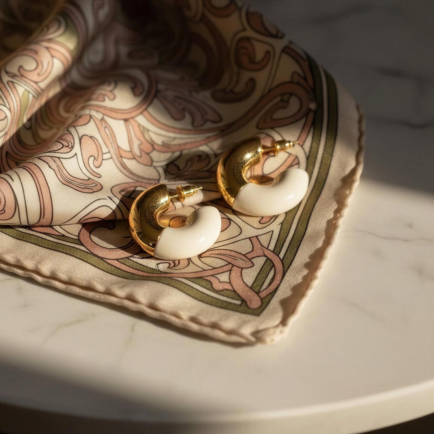 Gold and white hoop earrings on a patterned fabric