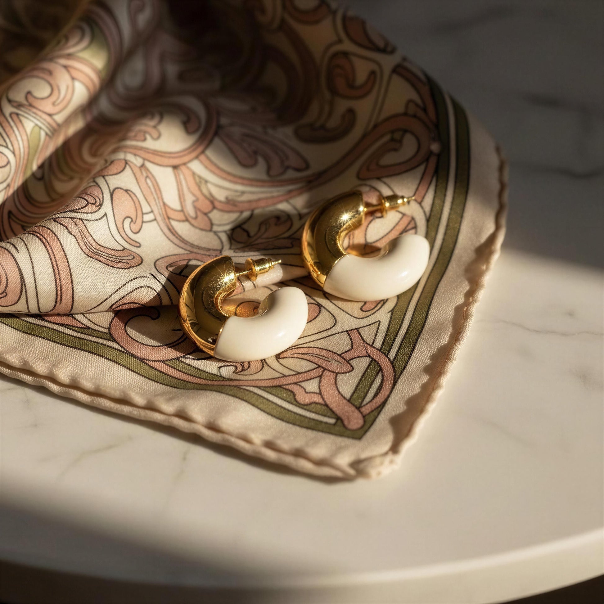Gold and white hoop earrings on a patterned fabric