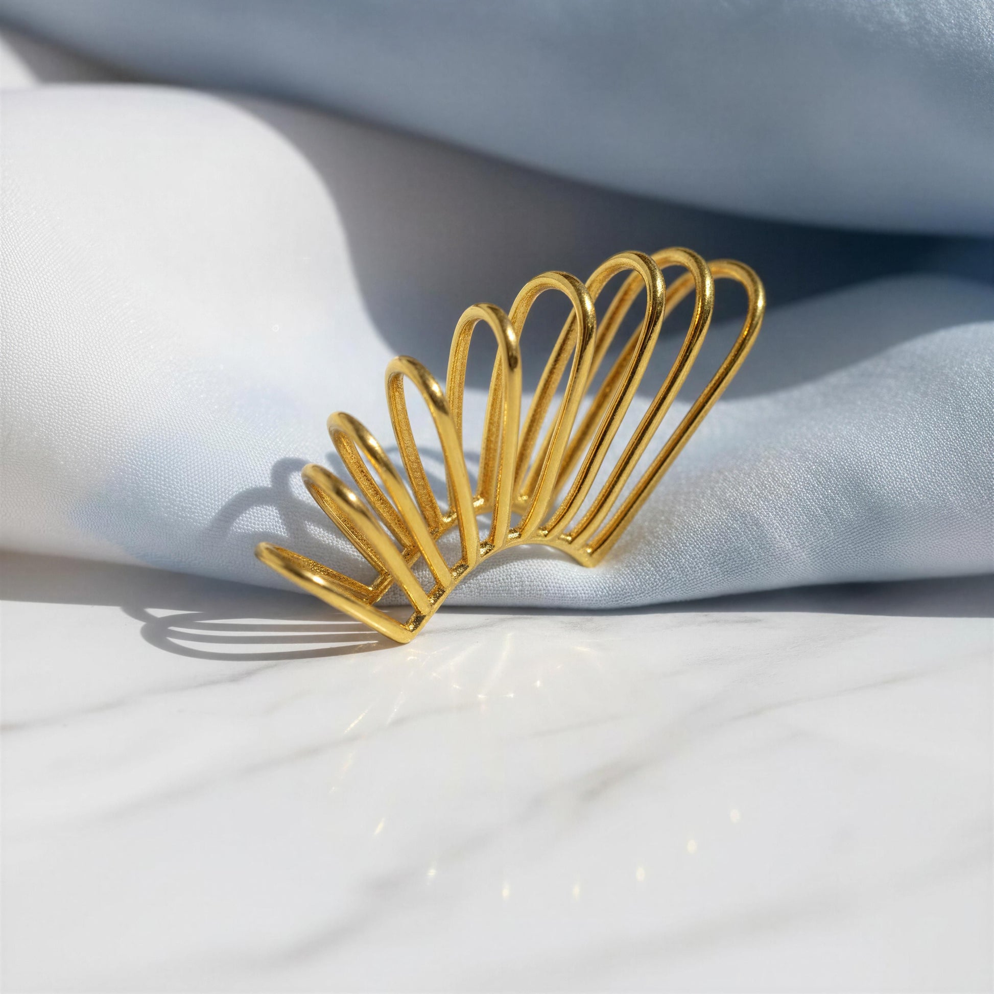 The Golden Horizon Ear Cuff on a white fabric background