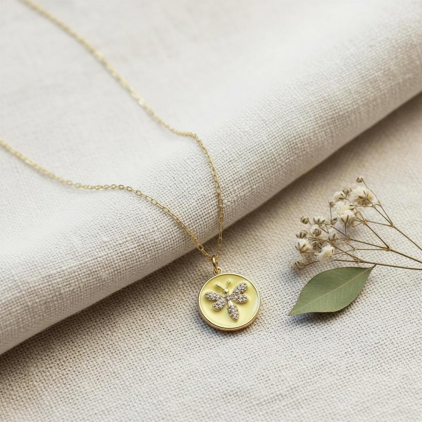 The Golden Wasp Medallion Necklace on a beige fabric background