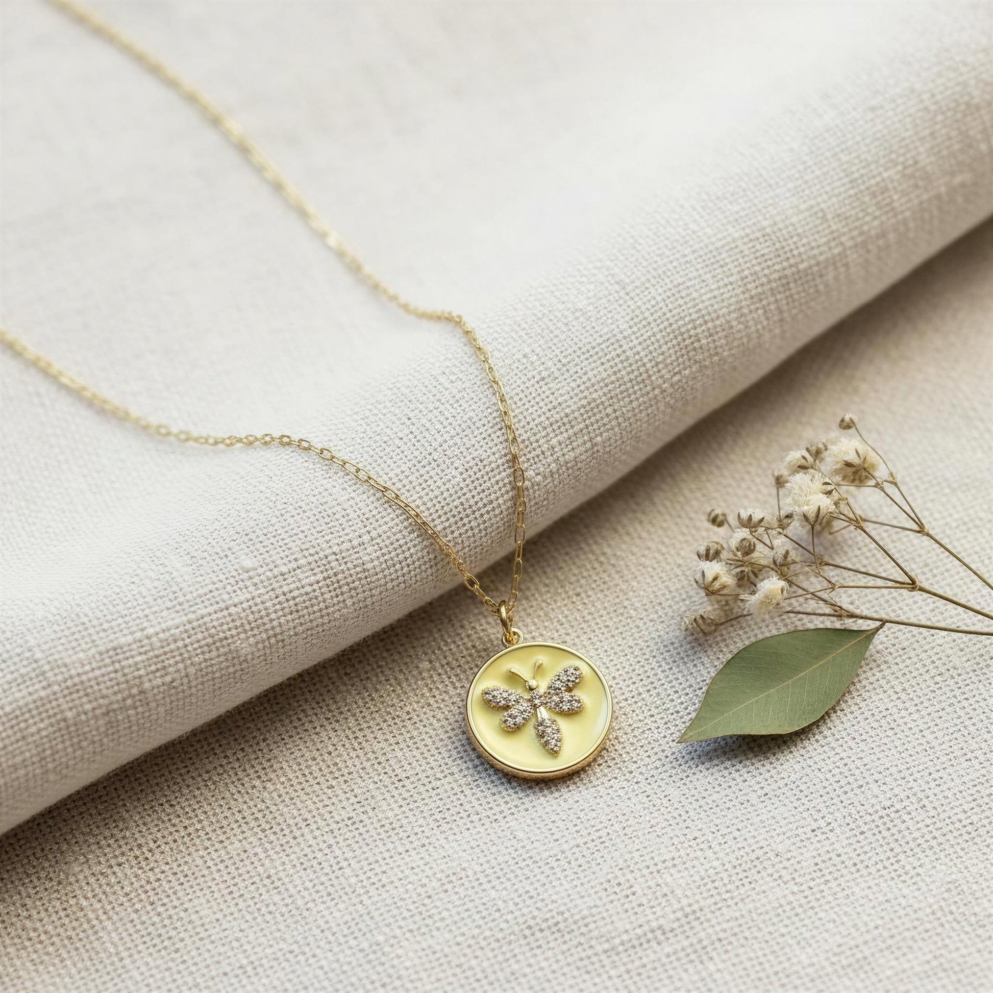 The Golden Wasp Medallion Necklace on a beige fabric background