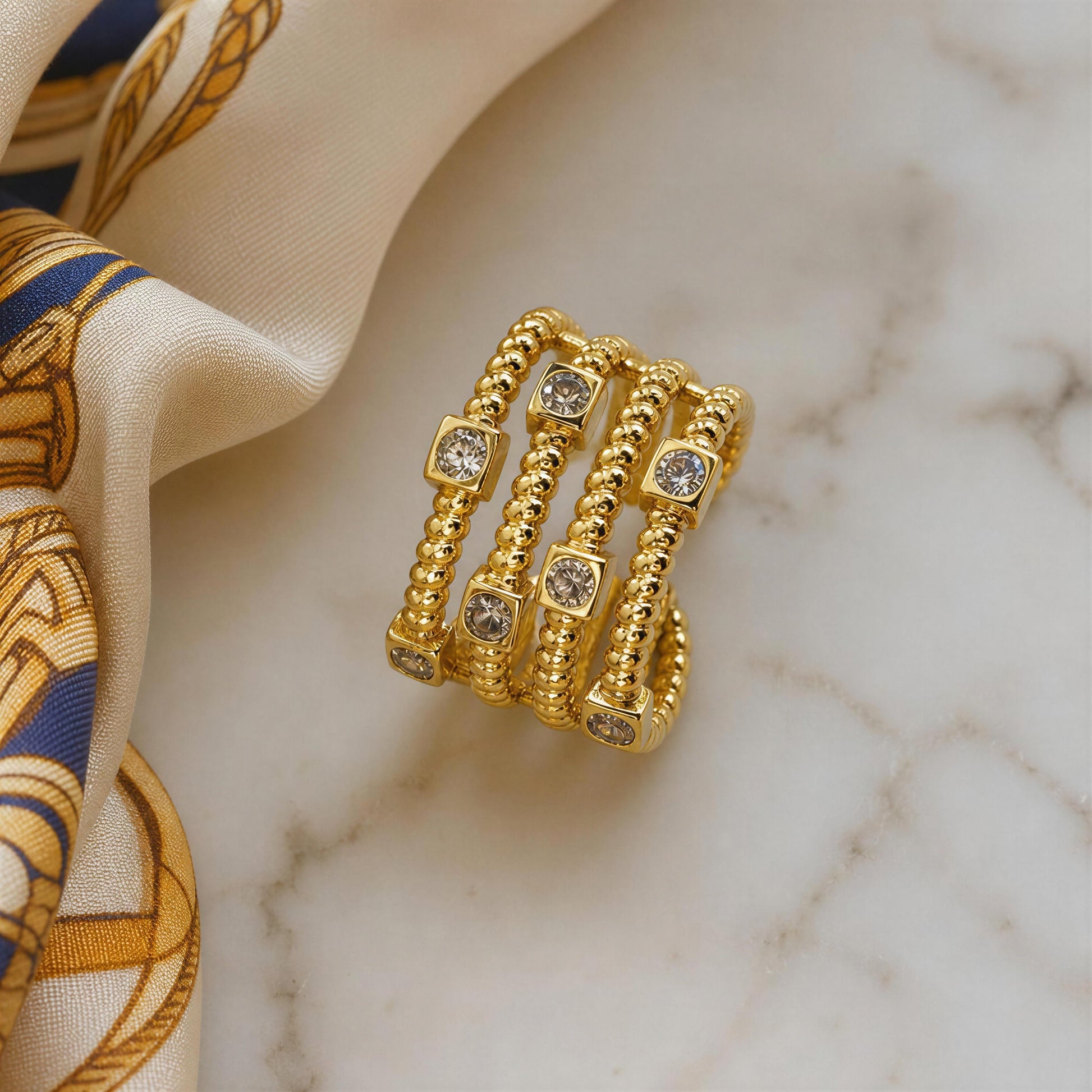 The Intreccio Ring from Chica Chica Jewelry against marble table and silk scarf.
