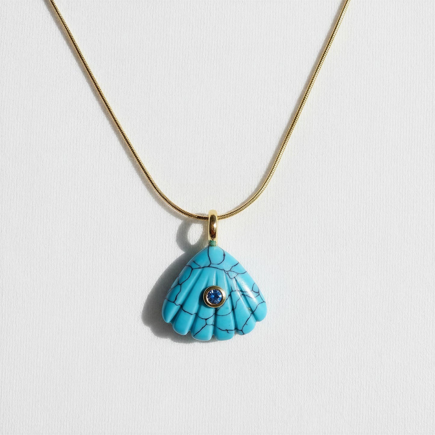 Turquoise shell pendant necklace on a white background