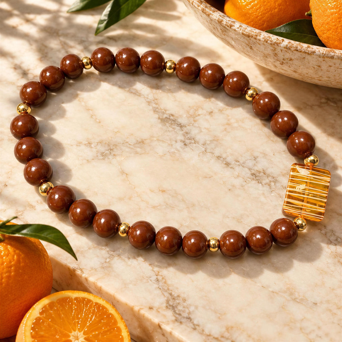 The Oranssi_Necklac from Chica_Chica_Jewelry flat laid on marble table next to oranges.
