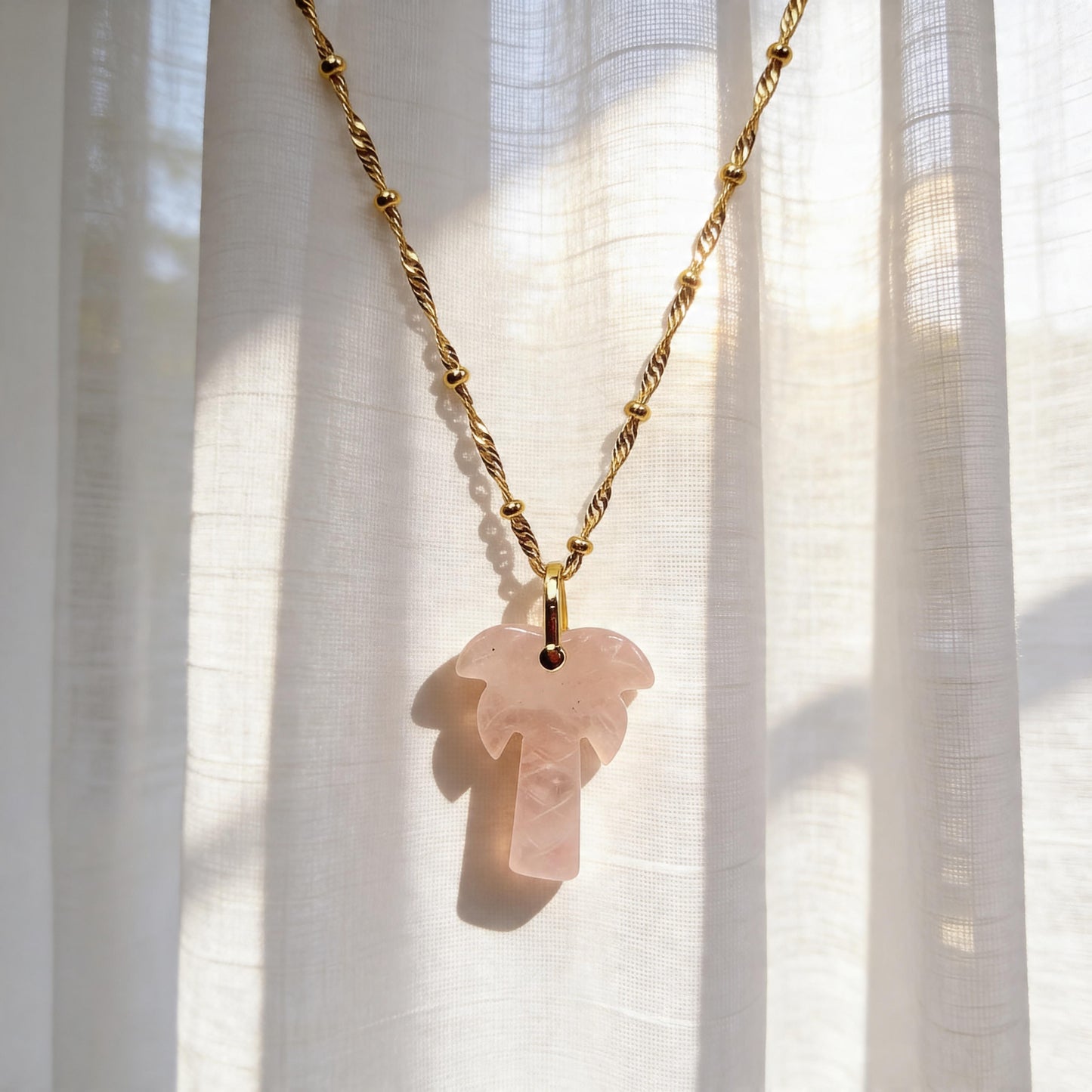 The Palma Rosa Long Necklace on a white curtain background