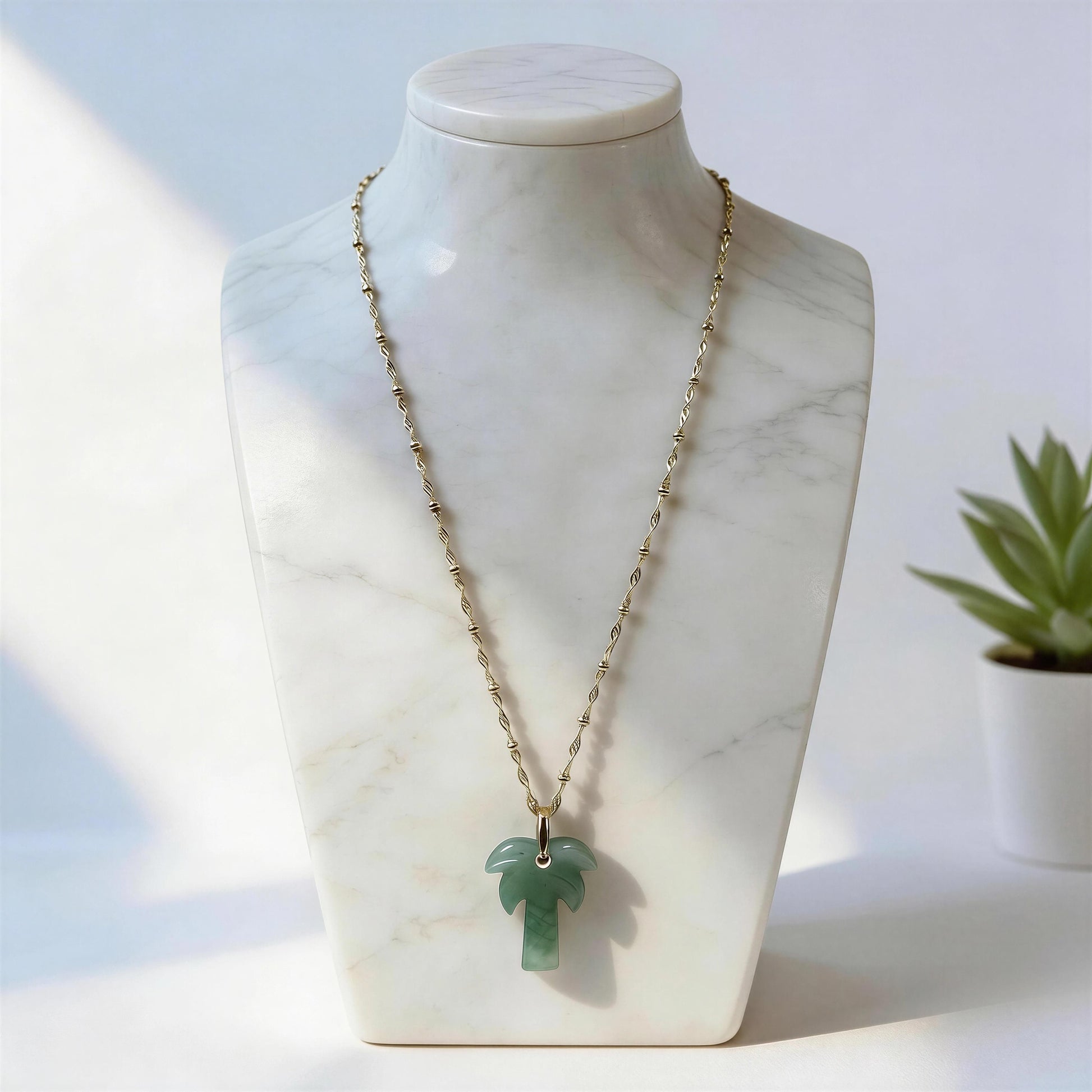 The Palma Verde Long Necklace on a marble bust against a light background