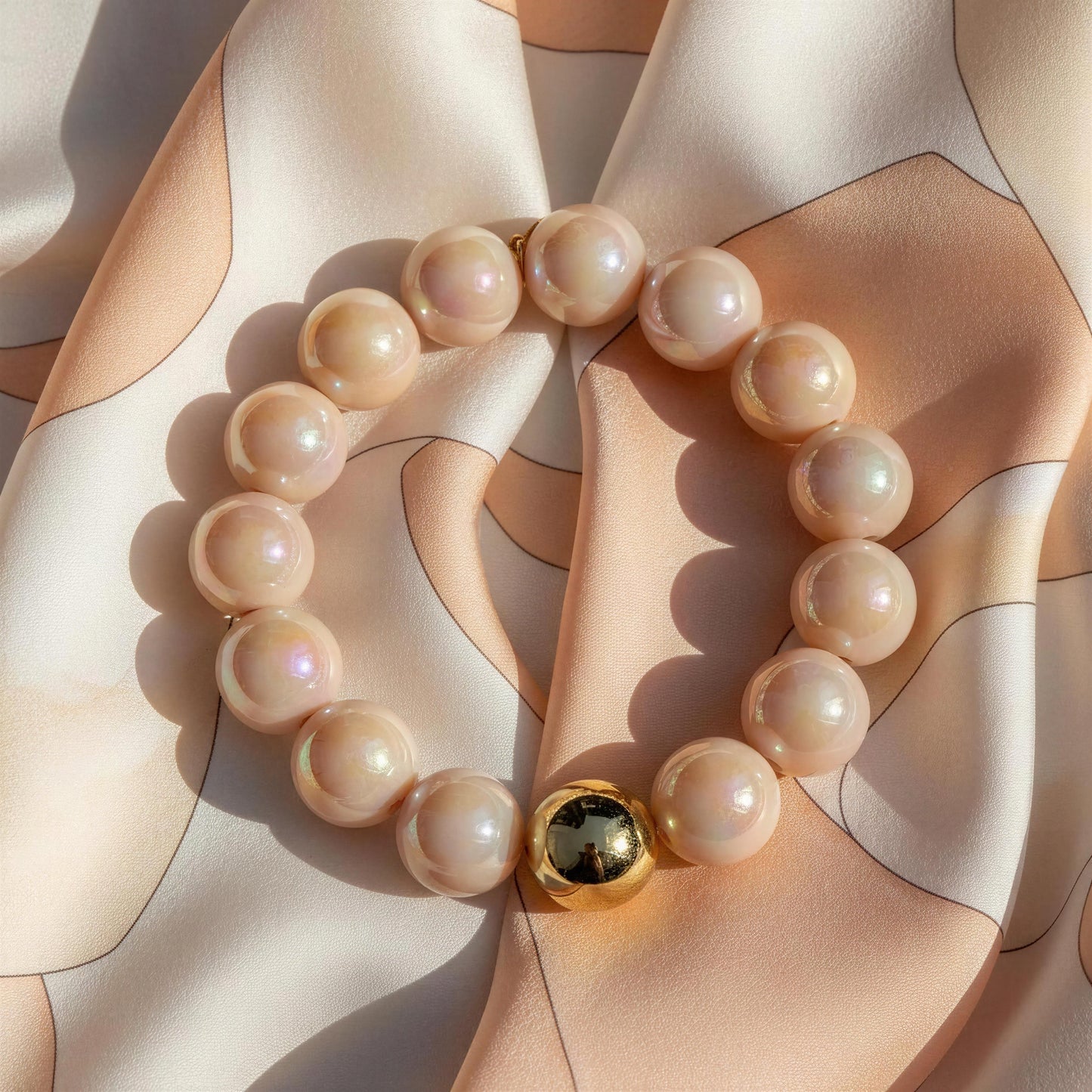 Peach  bracelet with a gold accent on a soft fabric background