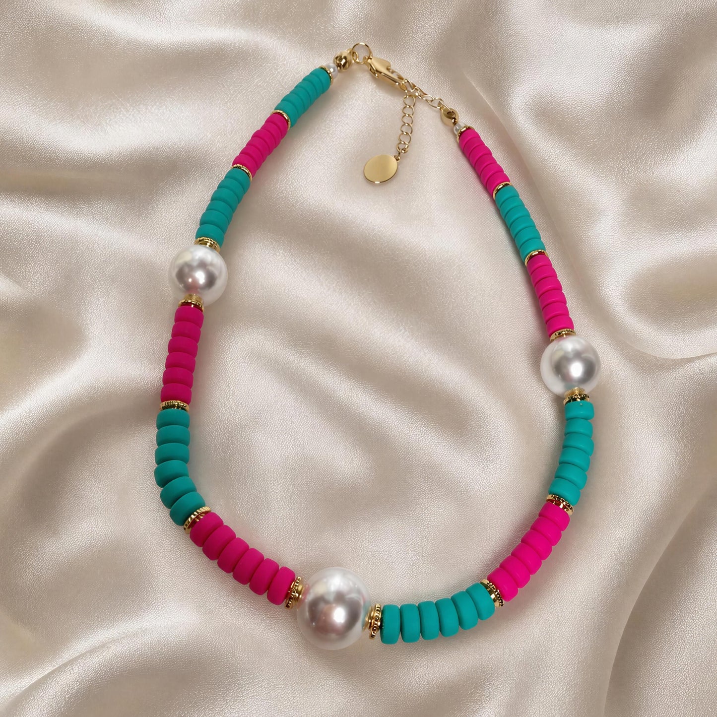 Necklace with pink and teal beads and pearls on a satin surface