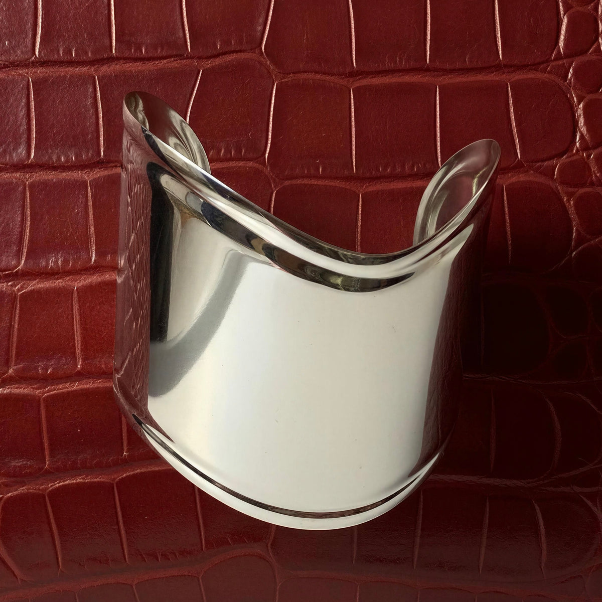 The Roma Cuff from Chica Chica Jewelry against a burgundy crocodile bag.