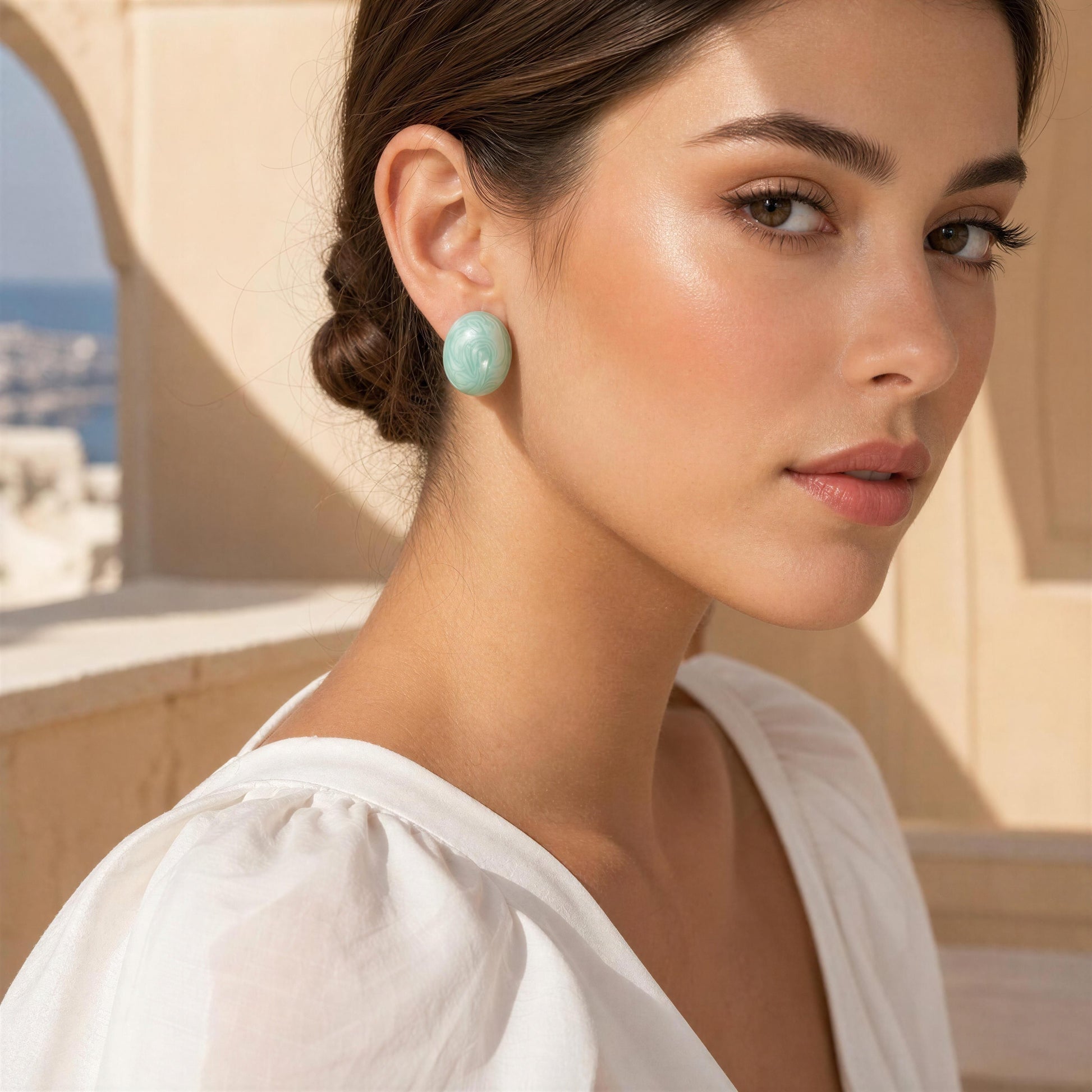 Woman wearing the  Rosina Studs -Aqua Glow earrings with a scenic background