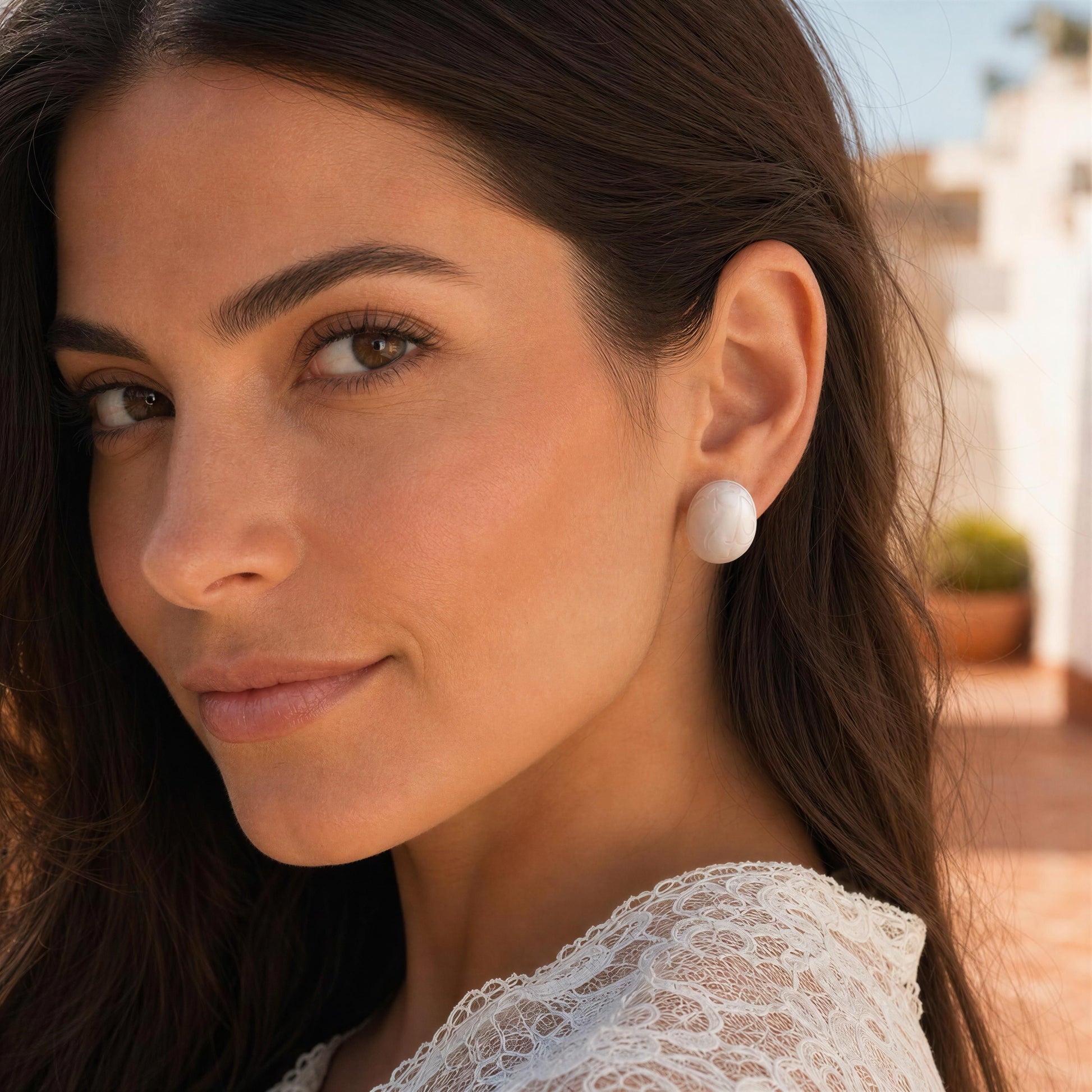 Close-up of a woman wearing the Rosina Studs - Ivory Mist with a blurred outdoor background