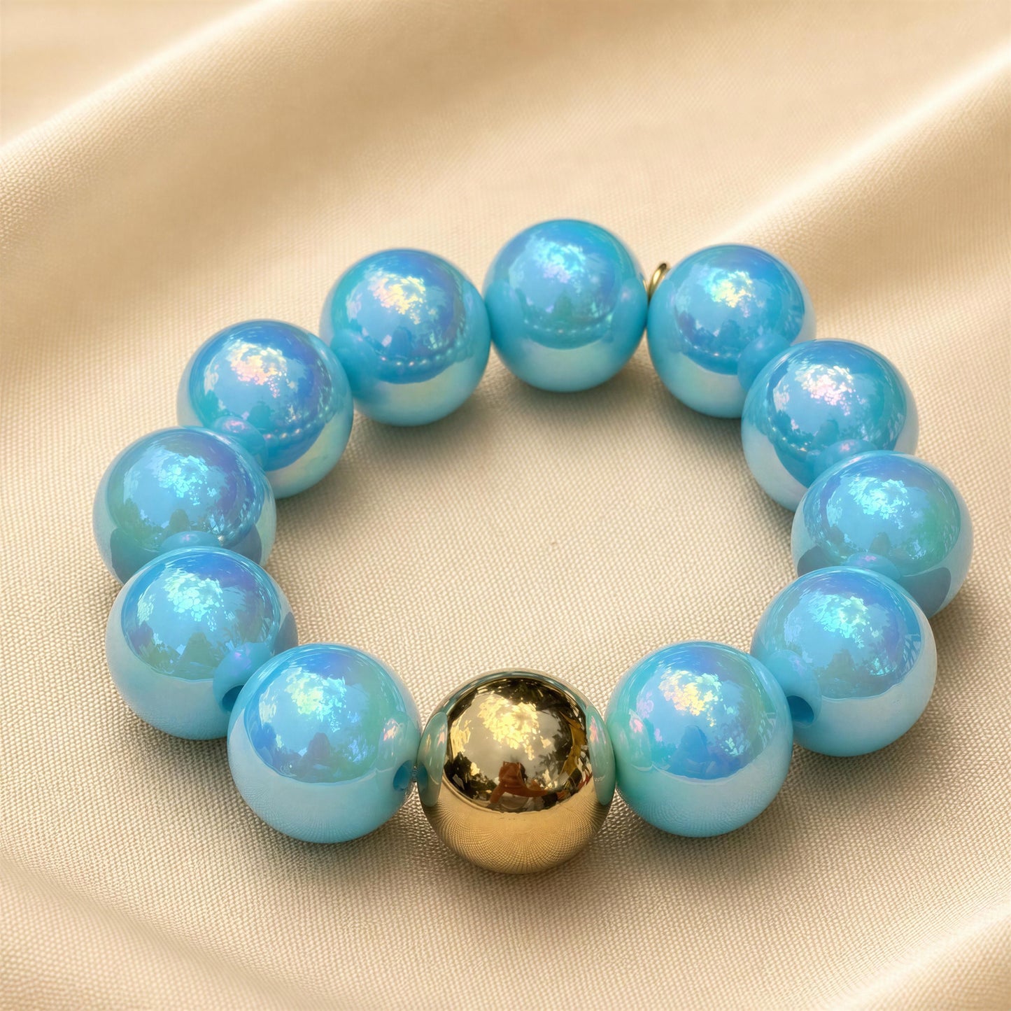 Turquoise beaded bracelet with a gold accent on a beige fabric background