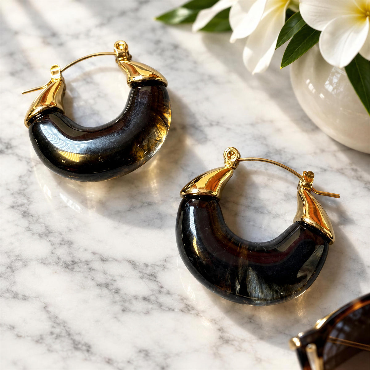 The Soraya Hoops – Black- Chica Chica Jewelry on white marble table next to sunglasses
