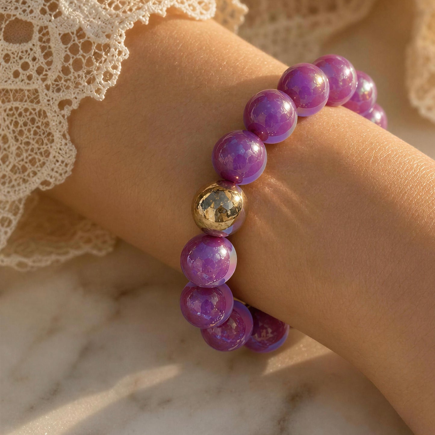 Purple beaded bracelet with a gold accent on a wrist against a lace and marble background