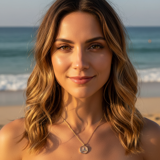 Woman with wavy hair standing on a beach with ocean in the background wearing Tidal Embrace Necklace