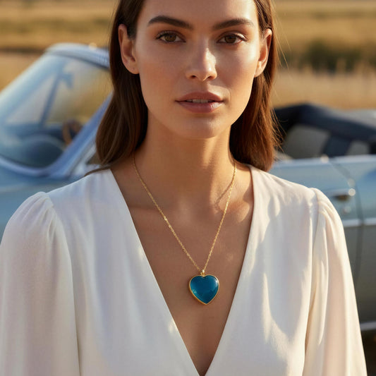 Woman wearing a white dress with the Turquoise Murano Heart necklace, standing in front of vintage cars.