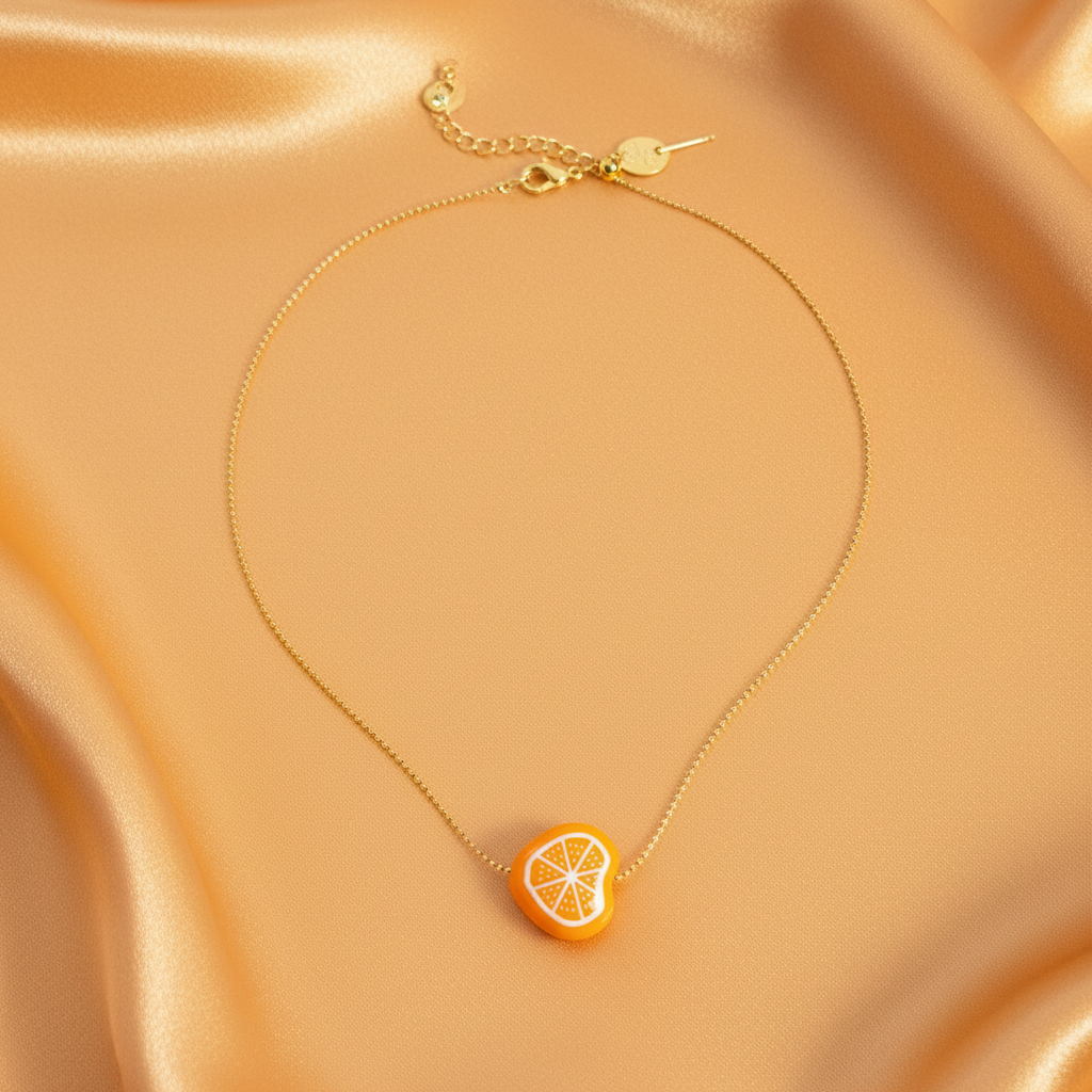 Tutti Frutti Orange charm necklace on soft golden fabric showing adjustable ball chain and clasp