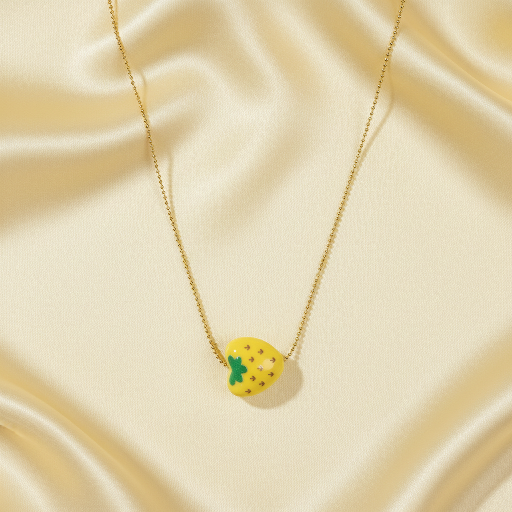 Tutti Frutti Pineapple Necklace with yellow pineapple charm displayed on soft golden fabric